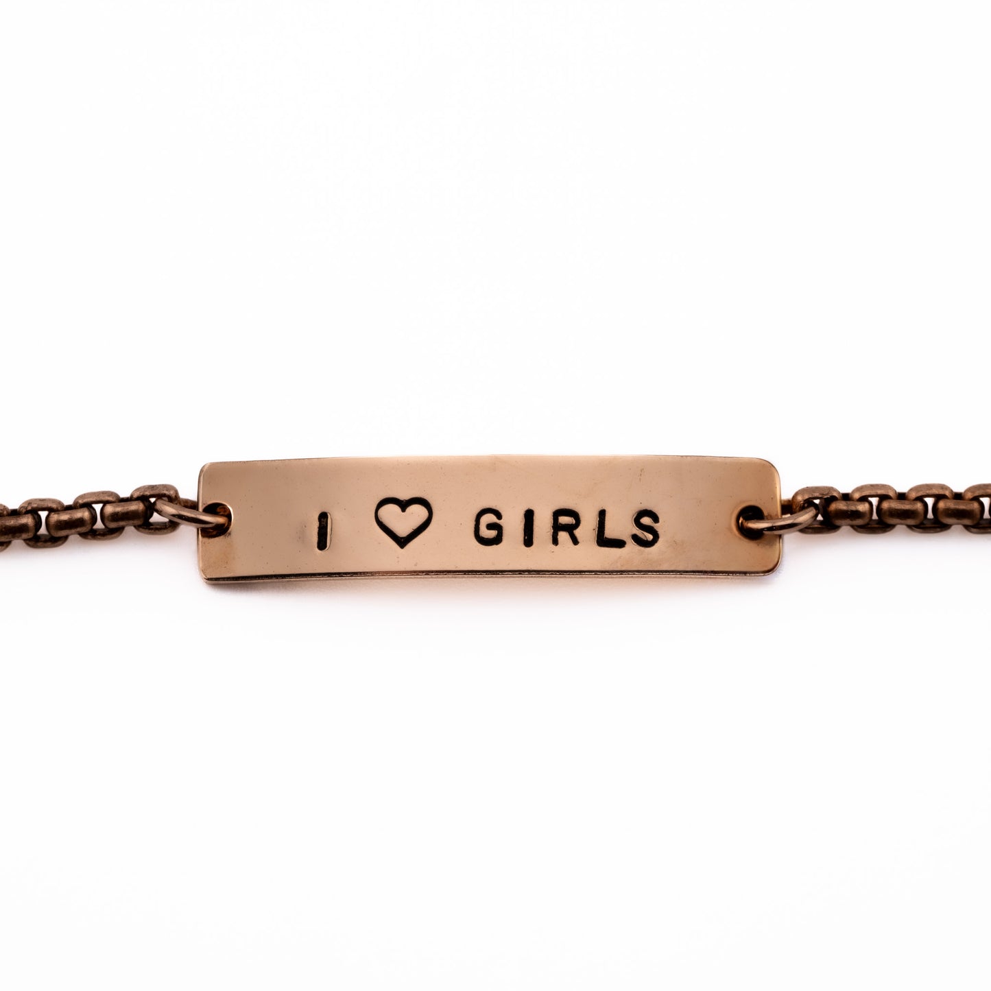 Close-up of I Heart Girls bronze bracelet with stamped heart symbol, lesbian pride