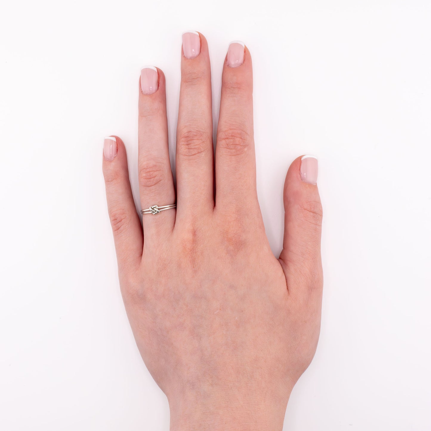 Love Knot stacking ring layered with other handmade rings in sterling silver and 14k gold-filled for everyday wear