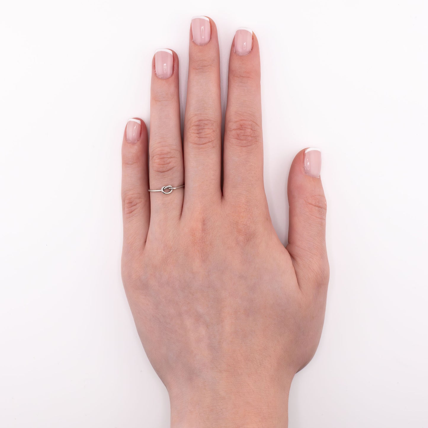 Sterling silver Tiny Knot stacking ring worn on hand, simple minimalist knot band for midi, pinky, or thumb styling
