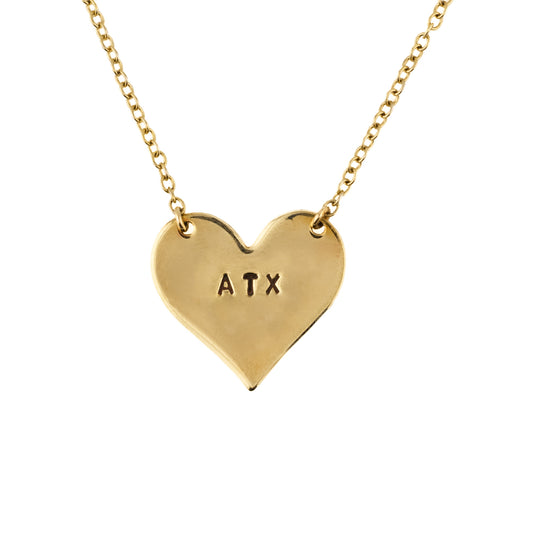 Gold heart-shaped necklace with 'ATX' engraving on a white background