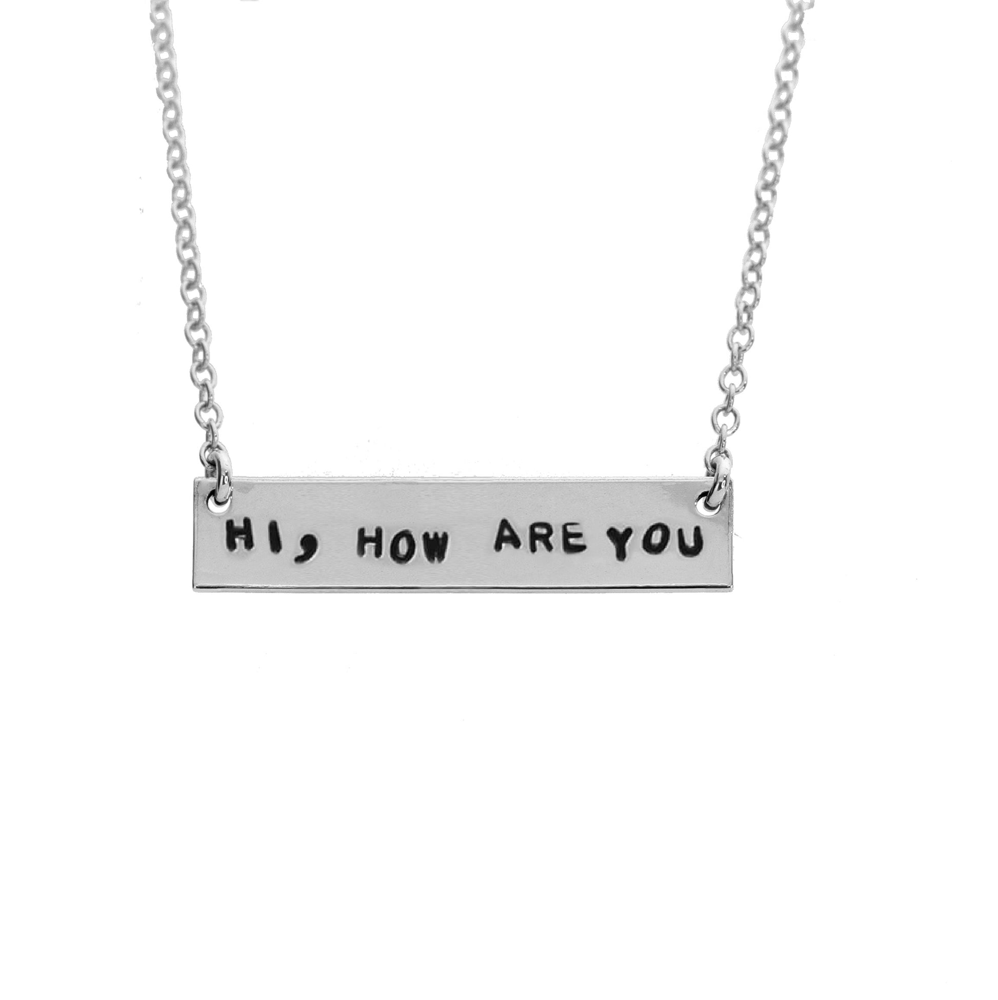 Sterling silver chain necklace with hand-stamped letters spelling out 'HI, HOW ARE YOU' and a small text below the chain.