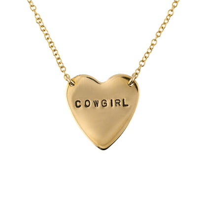 Gold heart-shaped necklace with 'COWGIRL' stamped on a white background