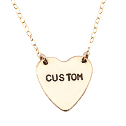 Gold heart-shaped necklace with 'CUSTOM' engraving on a white background