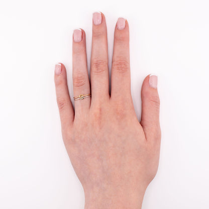 Duo Tone Love Knot ring in sterling silver and 14k gold-filled worn on hand, mixed metal knot jewelry symbolizing love and unity