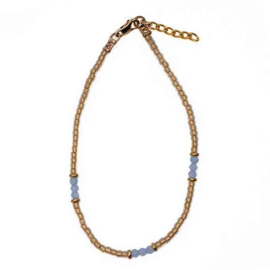 Overhead view of handmade Gold and Blue Seed Bead Anklet with soft tan gold glass beads, baby blue beads, and gold accents, jewelry made in Austin Texas