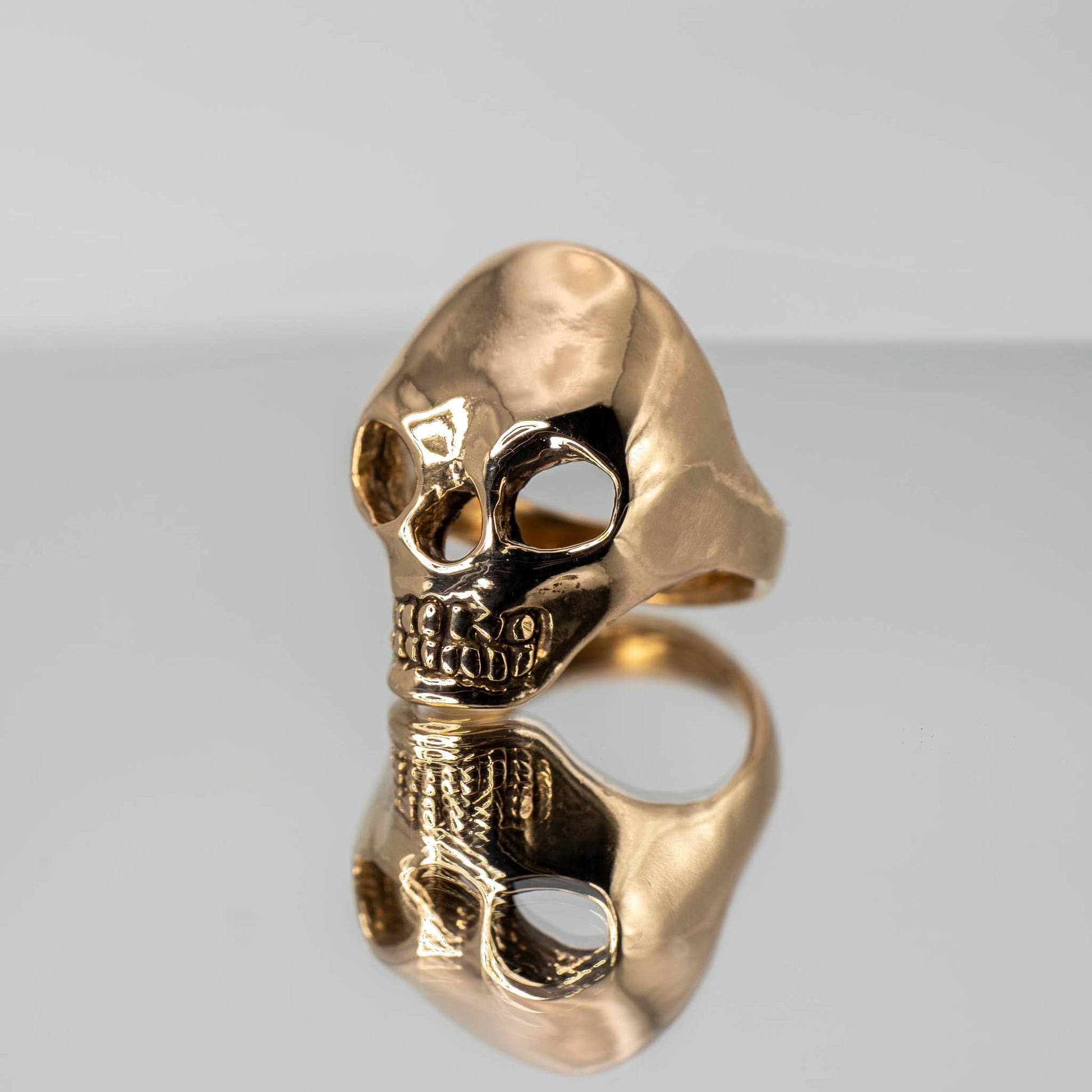 Bronze Skull Ring on mirror with reflection, handmade artisan jewelry crafted in Texas, USA