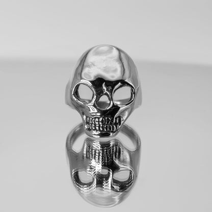 Artistic photo of sterling silver Skull Ring on mirror surface, handmade jewelry crafted in Austin, Texas
