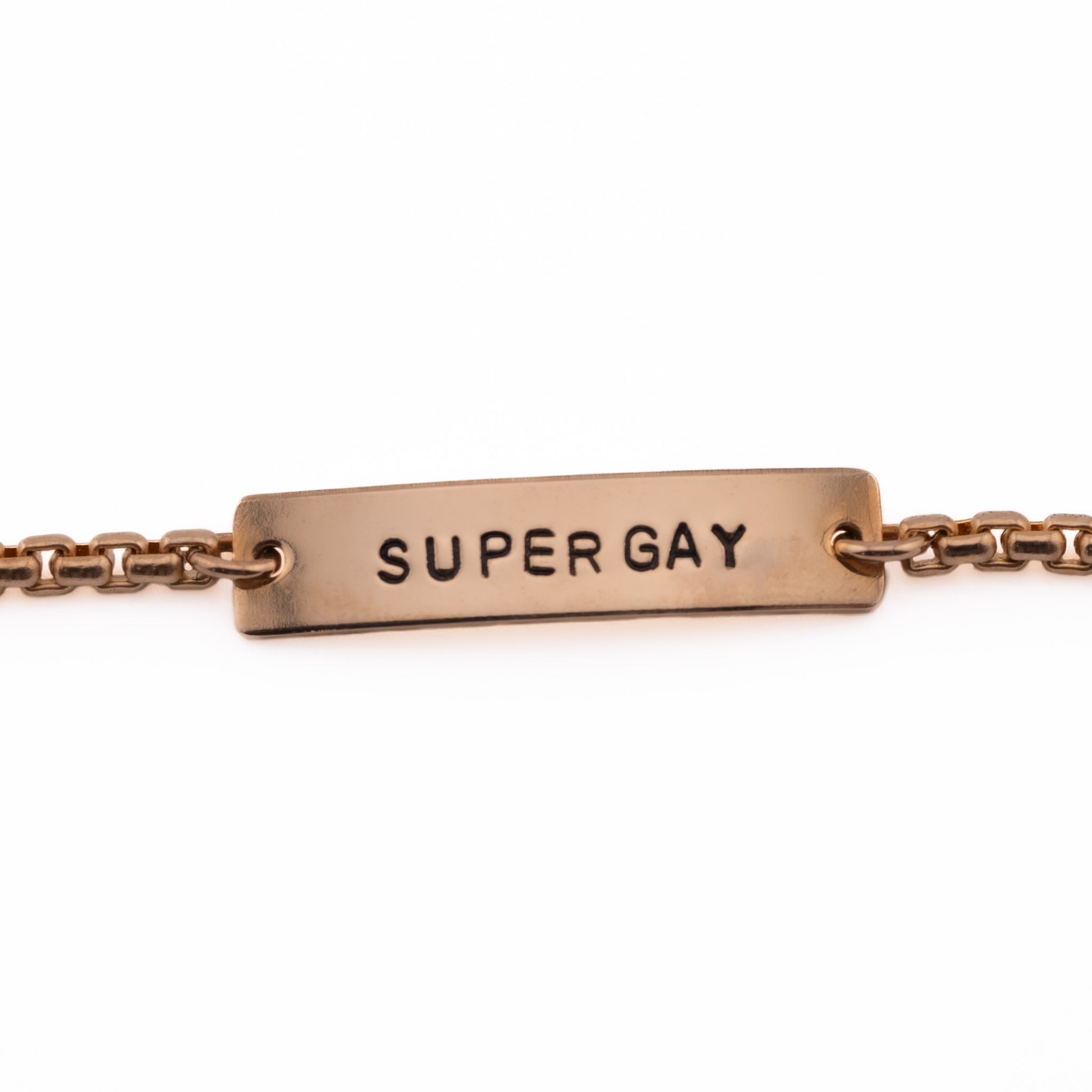 Close-up of Super Gay hand-stamped bronze bracelet handmade in Austin