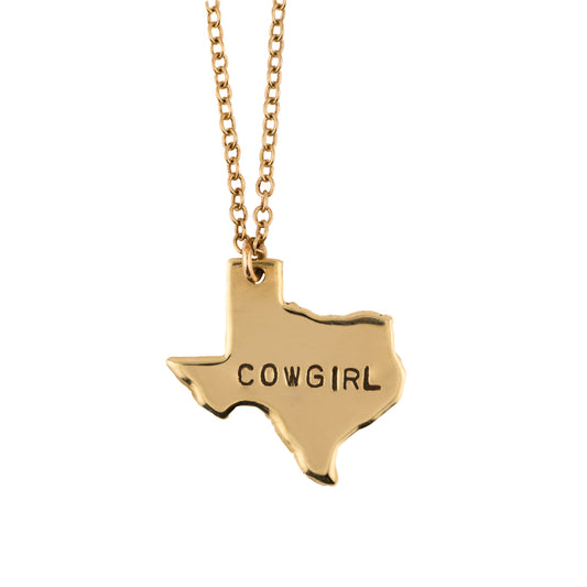 Gold necklace with a Texas-shaped pendant that reads 'COWGIRL' on a white background