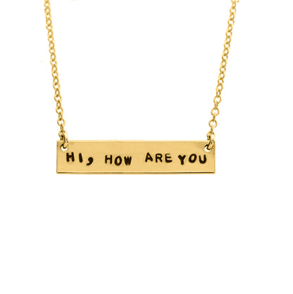 Gold-filled chain necklace with hand-stamped letters spelling out 'HI, HOW ARE YOU' and a small text below the chain.